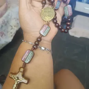 Cliente com o terço no pulso mostrando a medalha dourada